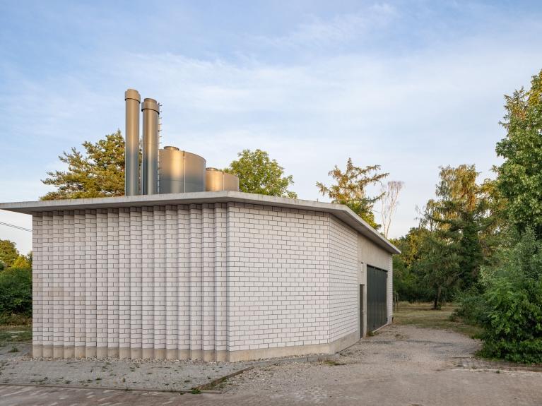 Außenaufnahme eines kleinen, kompakten Gebäudes mit einer Fassade aus hellen Backsteinen. Es handelt sich um ein Versorgungsgebäude.