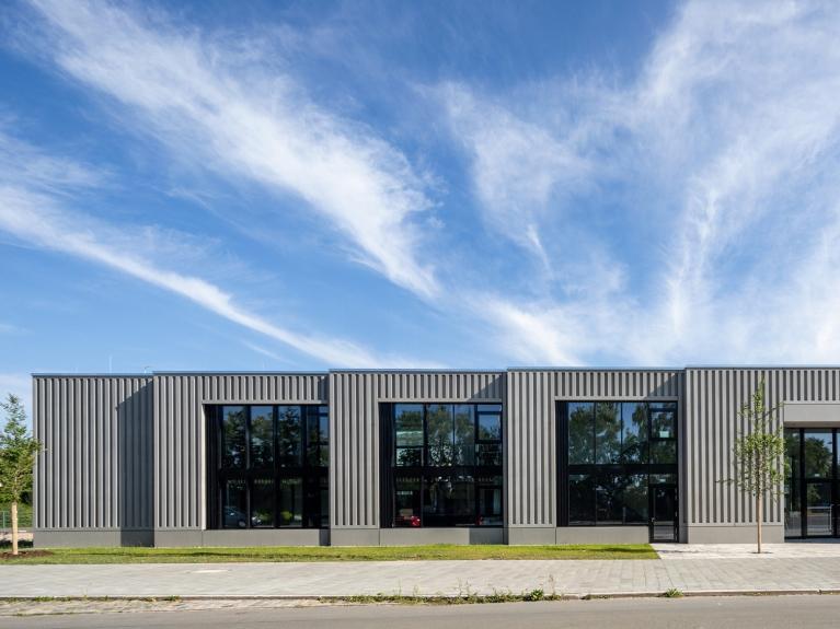 Außenaufnahme eines modernen, flachen Gebäudes mit einer Fassade aus vertikal strukturierten Paneelen. Das Gebäude ist Teil des Bauindustriezentrum in Nürnberg.