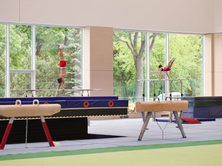 Innenaufnahme einer modernen Turnhalle im olympischen und paralympischen Trainingszentrum in Grünheide. Große Fenster und schöner Ausblick auf die Natur.  Realisierung eines klimaneutralen Energiekonzeptes für das Trainingszentrum.