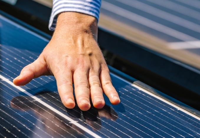 Foto einer Hand auf einer Photovoltaik-Anlage mit sichtbaren Solarzellen