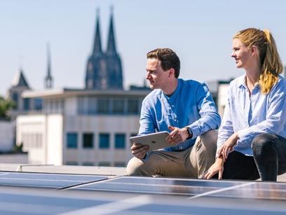 Foto mit zwei Personen auf einem Dach mit einer Photovoltaik-Anlage